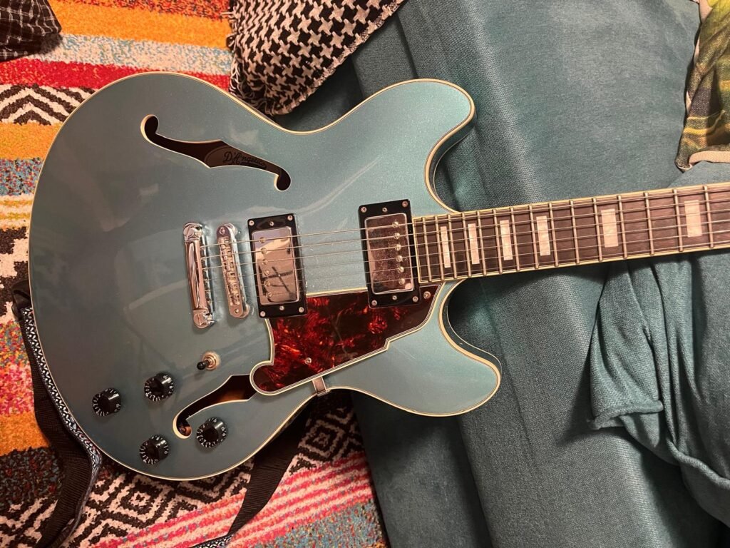 Close-up of a blue electric guitar on a colorful rug.