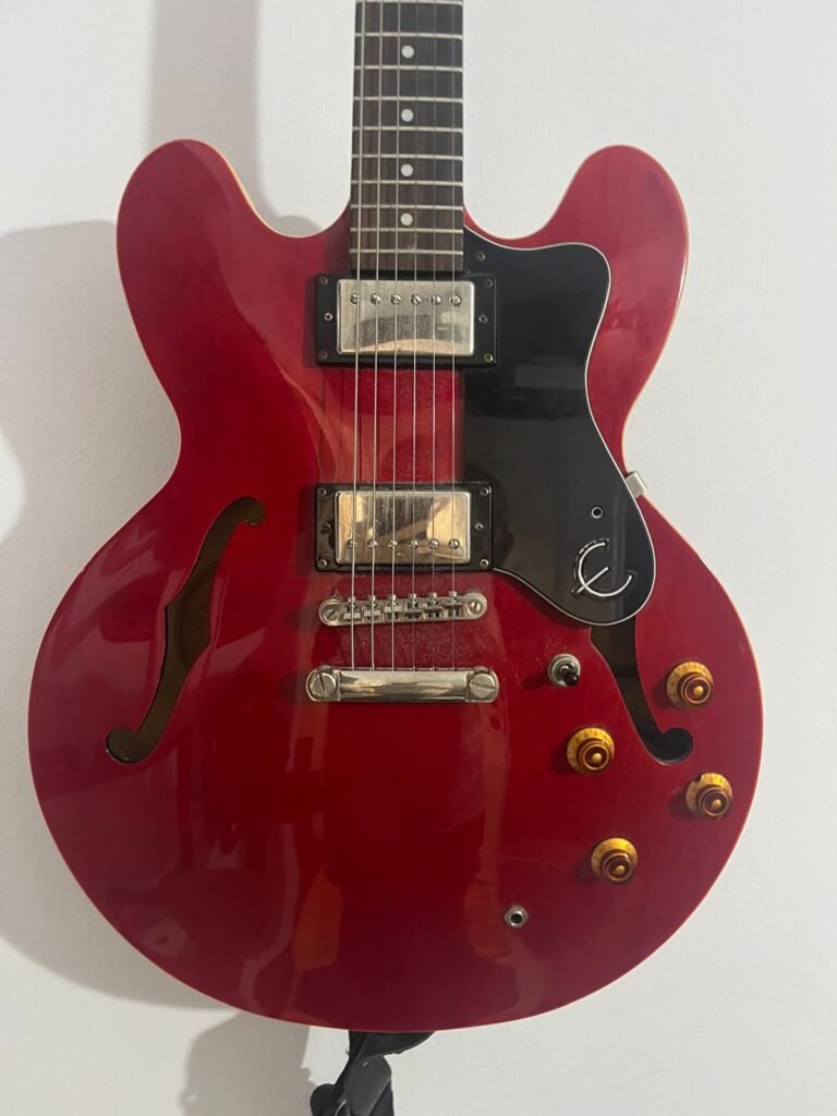 Close-up of a red electric guitar with a black pickguard.