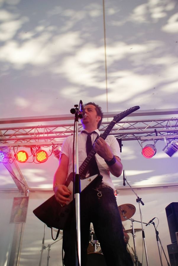 Guitarist performing live on stage with colored lights